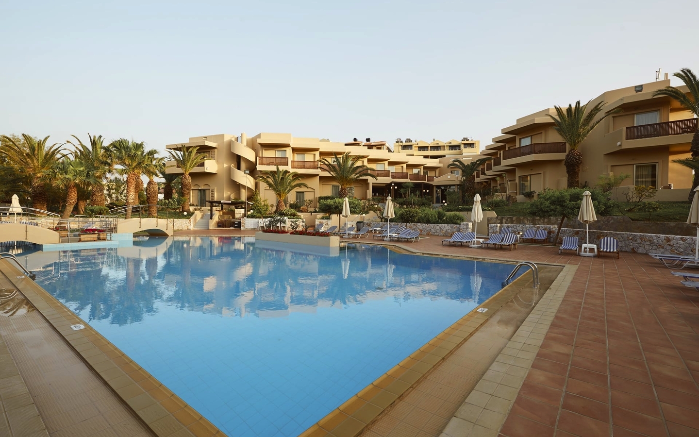 Hotelpool mit Liegestühlen und Palmen im Giannoulis Santa Marina Beach, Kreta.