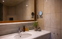 Badezimmer mit Waschbecken, Spiegel, Seifenspender und Pflanzen.