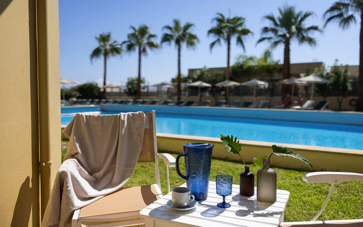Blick vom Double Room auf Pool mit Palmen im Santa Marina Plaza Hotel, Kreta.