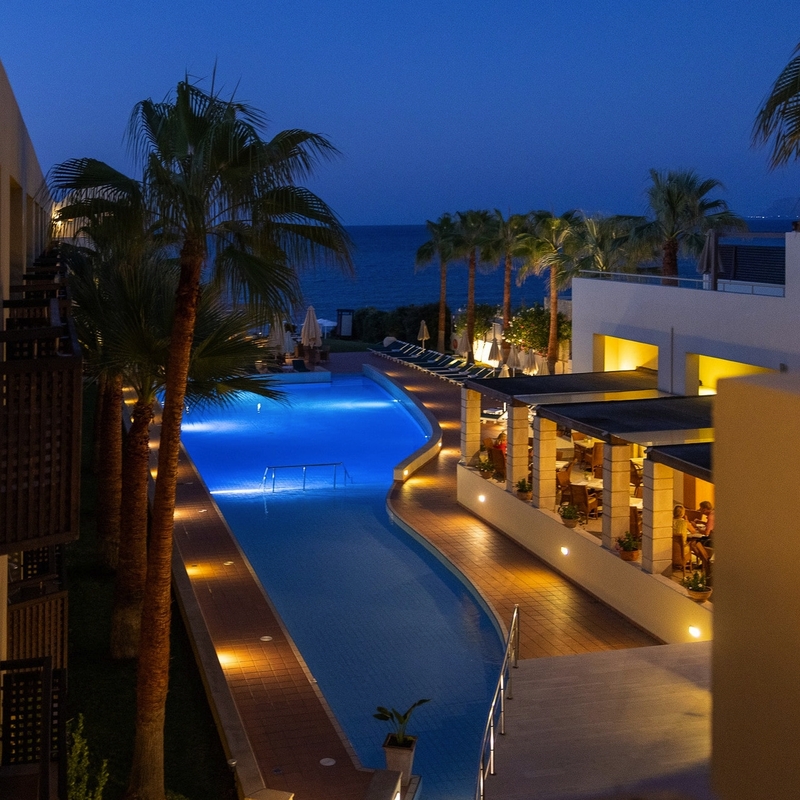 Hotelpool bei Nacht mit Meerblick und Palmen in Kreta.