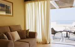 Juniorsuite mit Sofa, Blick auf Terrasse und Meer.