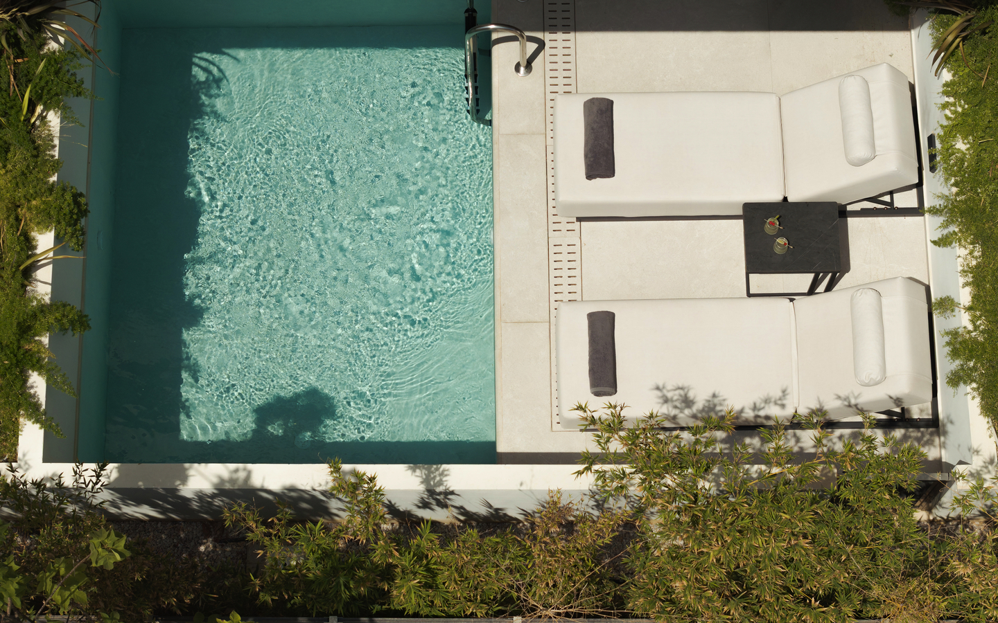 Blick von oben auf einen kleinen Pool und zwei Liegen im Hotel in Kreta.