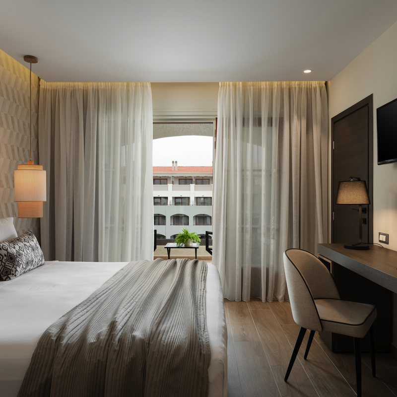 Zimmer mit Doppelbett, modernem Dekor und Blick auf den Pool.