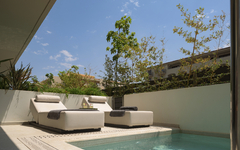 Sonnige Terrasse mit Pool und zwei Liegestühlen im Hotel The Artemis Palace, Kreta.