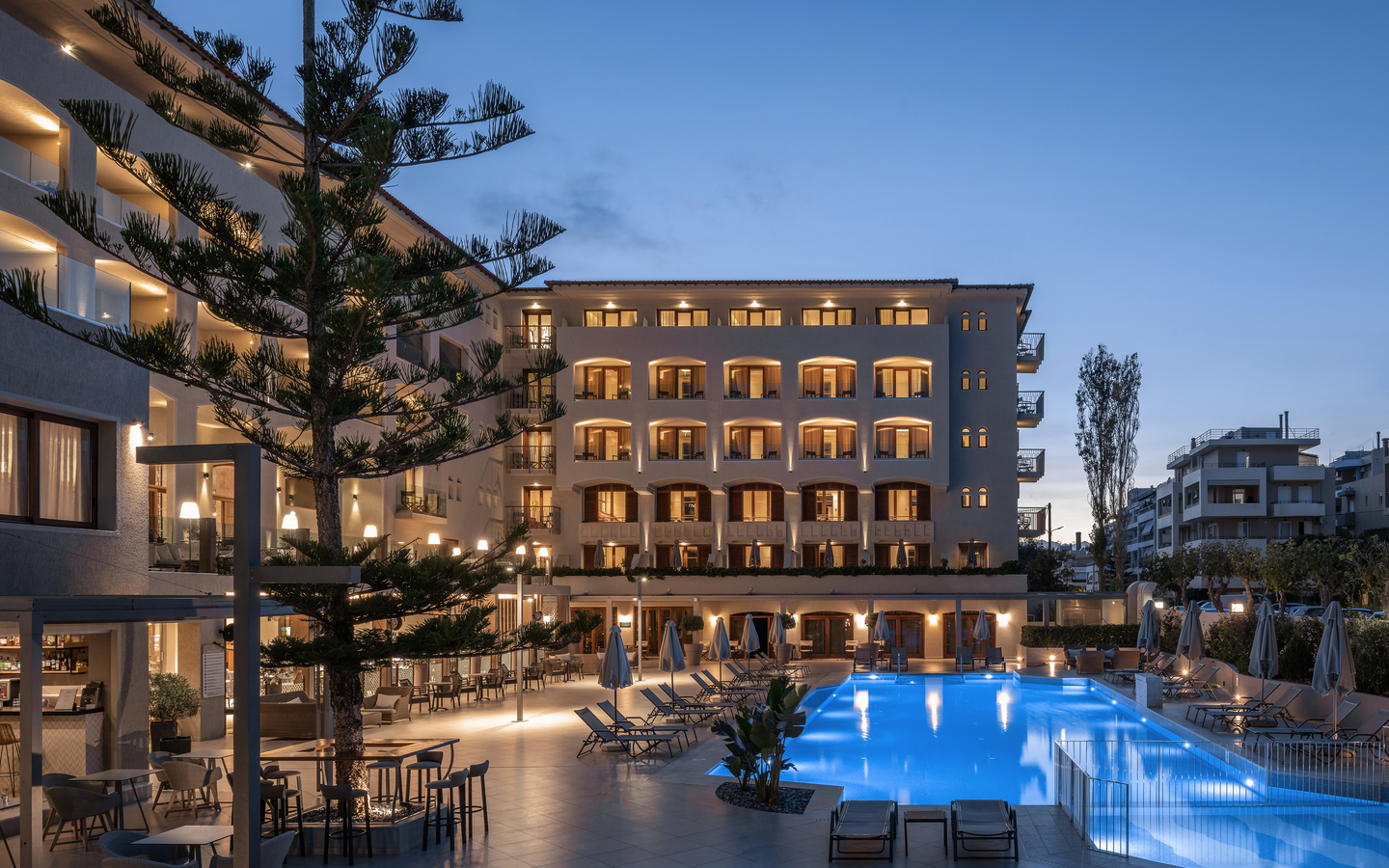 Außenansicht des Hotels Theartemis Palace mit Pool bei Dämmerung.