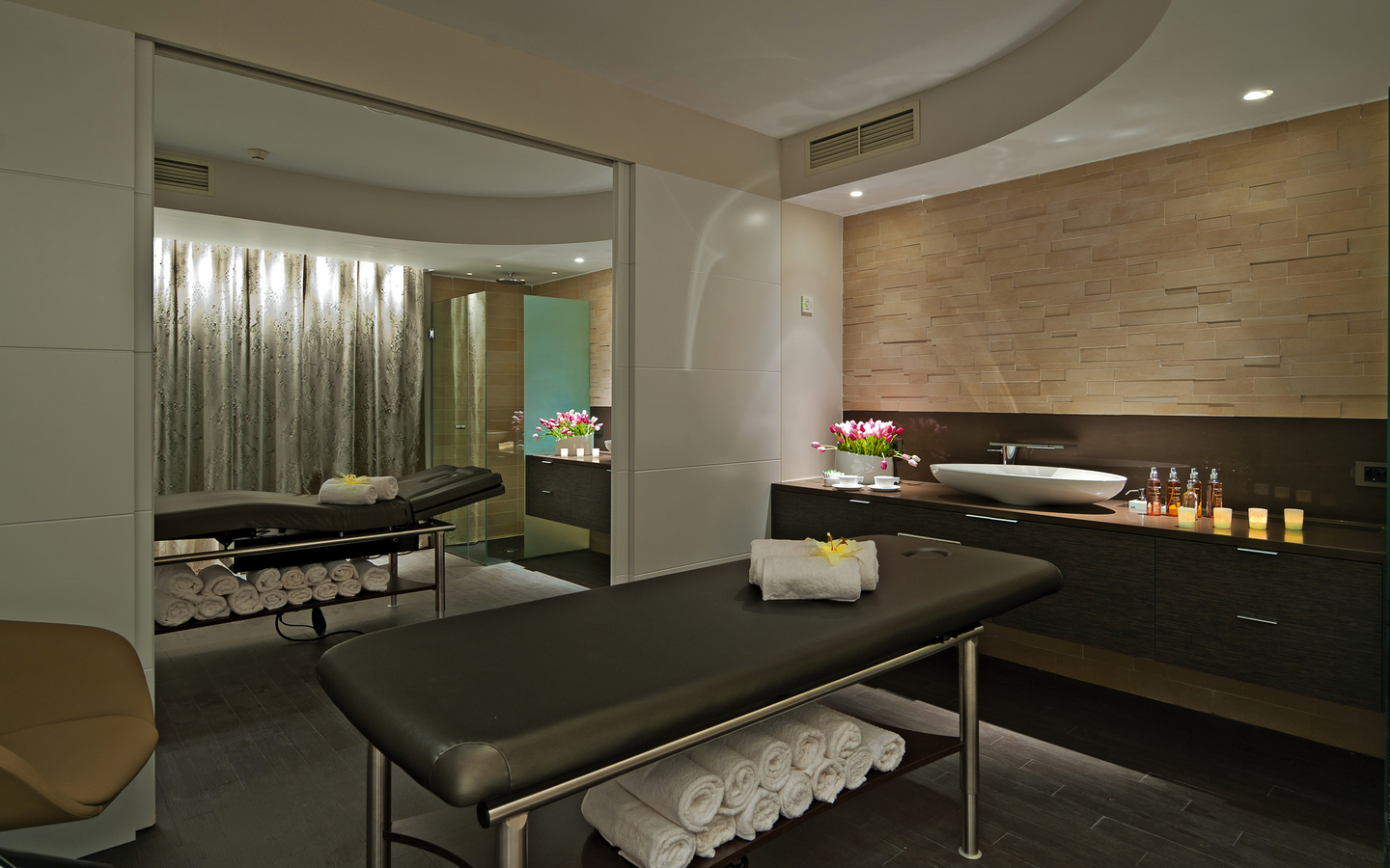 Massageraum mit Liege, Handtüchern und entspannender Beleuchtung