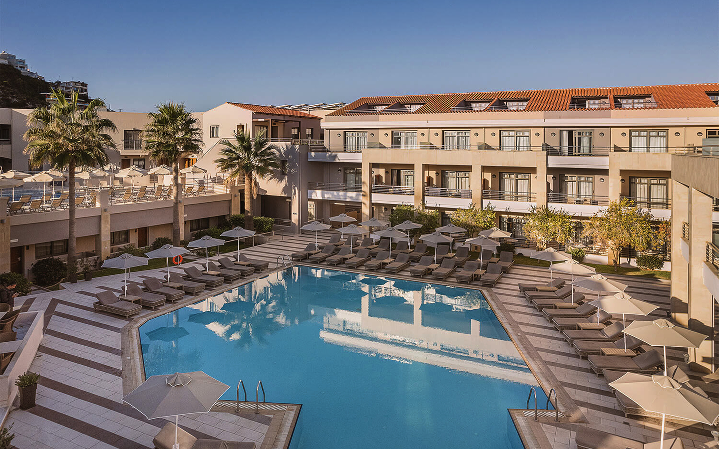 Poolbereich des Porto Platanias Beach Resort and Spa mit Liegestühlen und Sonnenschirmen