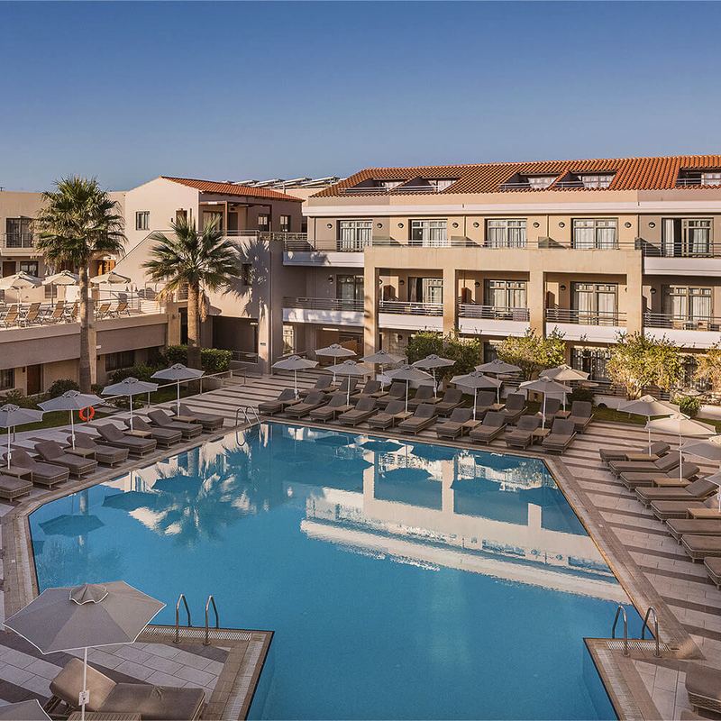 Poolbereich des Porto Platanias Beach Resort and Spa mit Liegestühlen und Sonnenschirmen