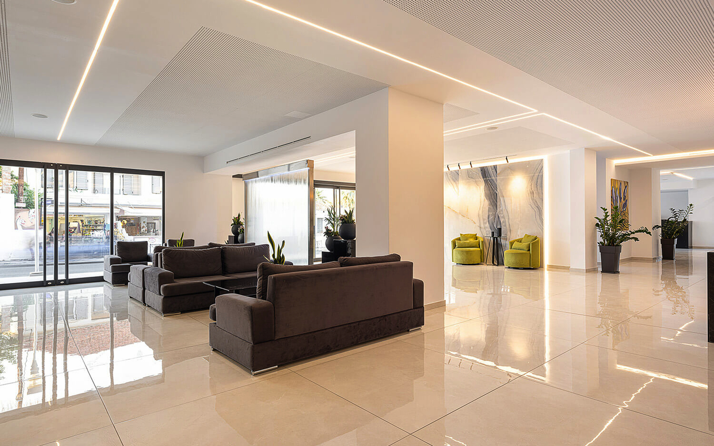 Moderne Hotellobby mit Sofas, Pflanzen und Glastüren.