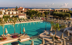 Poollandschaft im Hotel Porto Platanias Village Resort auf Kreta, umgeben von Liegestühlen.