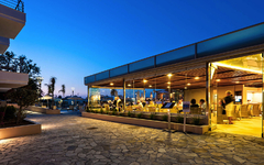 Hotelaußenbereich bei Dämmerung mit Gästen im Restaurant.