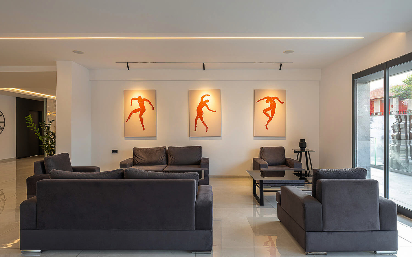 Lobby mit grauen Sofas und Kunst an der Wand im Hotel Porto Platanias Village Resort.