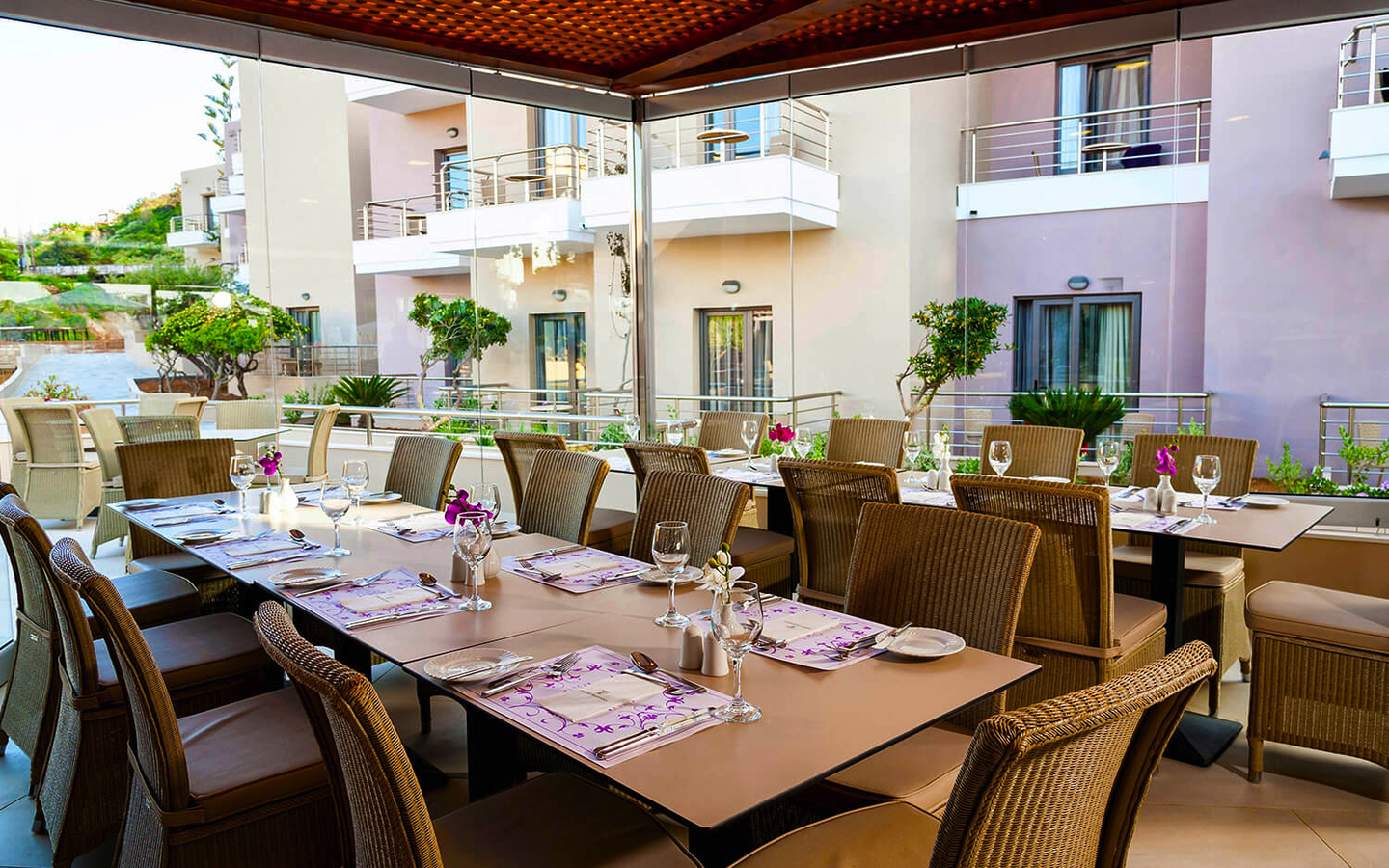 Gedeckter Tisch auf einer Terrasse mit Blick auf Hotelbalkone und Pflanzen.
