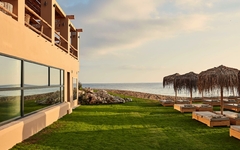 Hotel mit Rasenfläche, Liegen und Meerblick bei Sonnenuntergang auf Kreta.