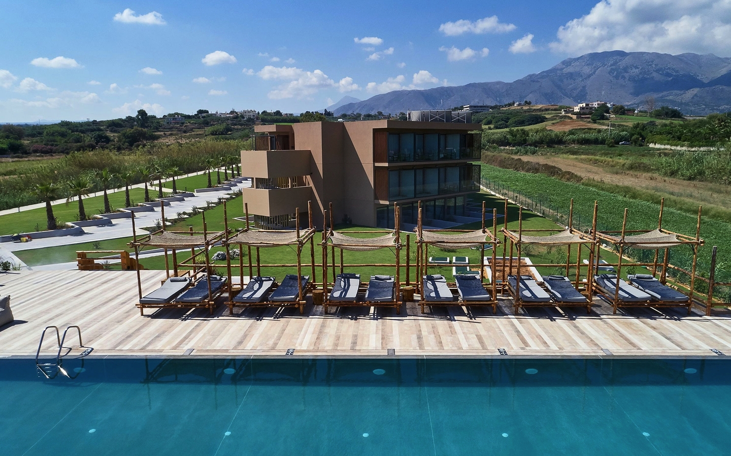 Außenansicht eines Hotels mit Pool und Sonnenliegen auf Kreta, Griechenland.