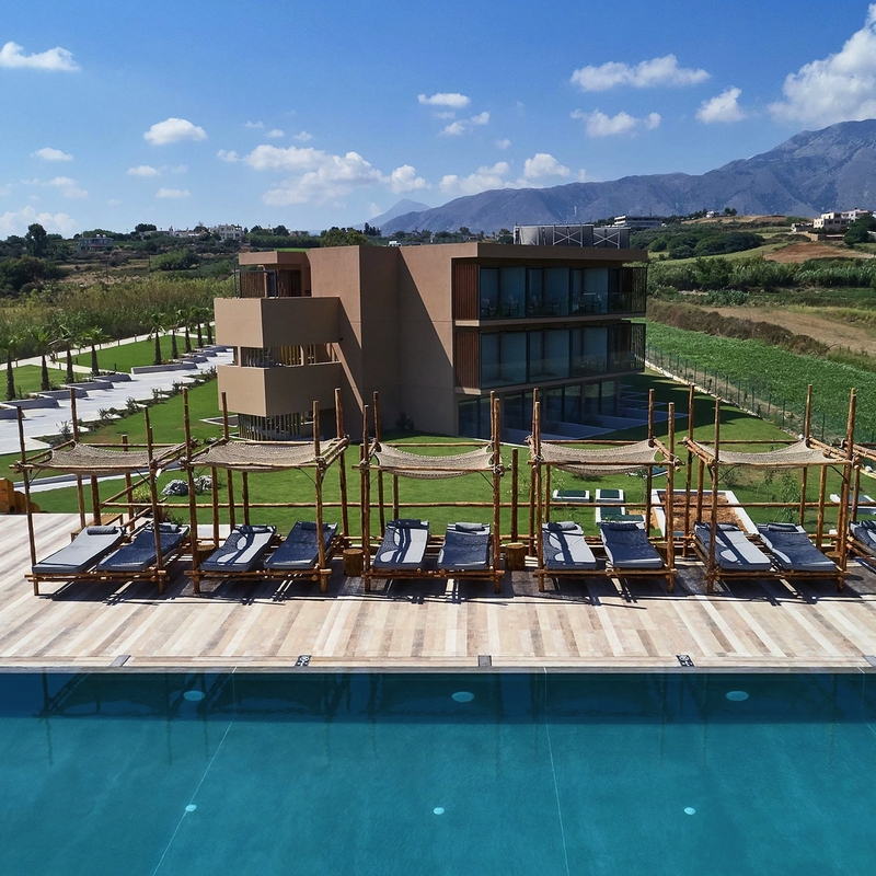 Außenansicht eines Hotels mit Pool und Sonnenliegen auf Kreta, Griechenland.