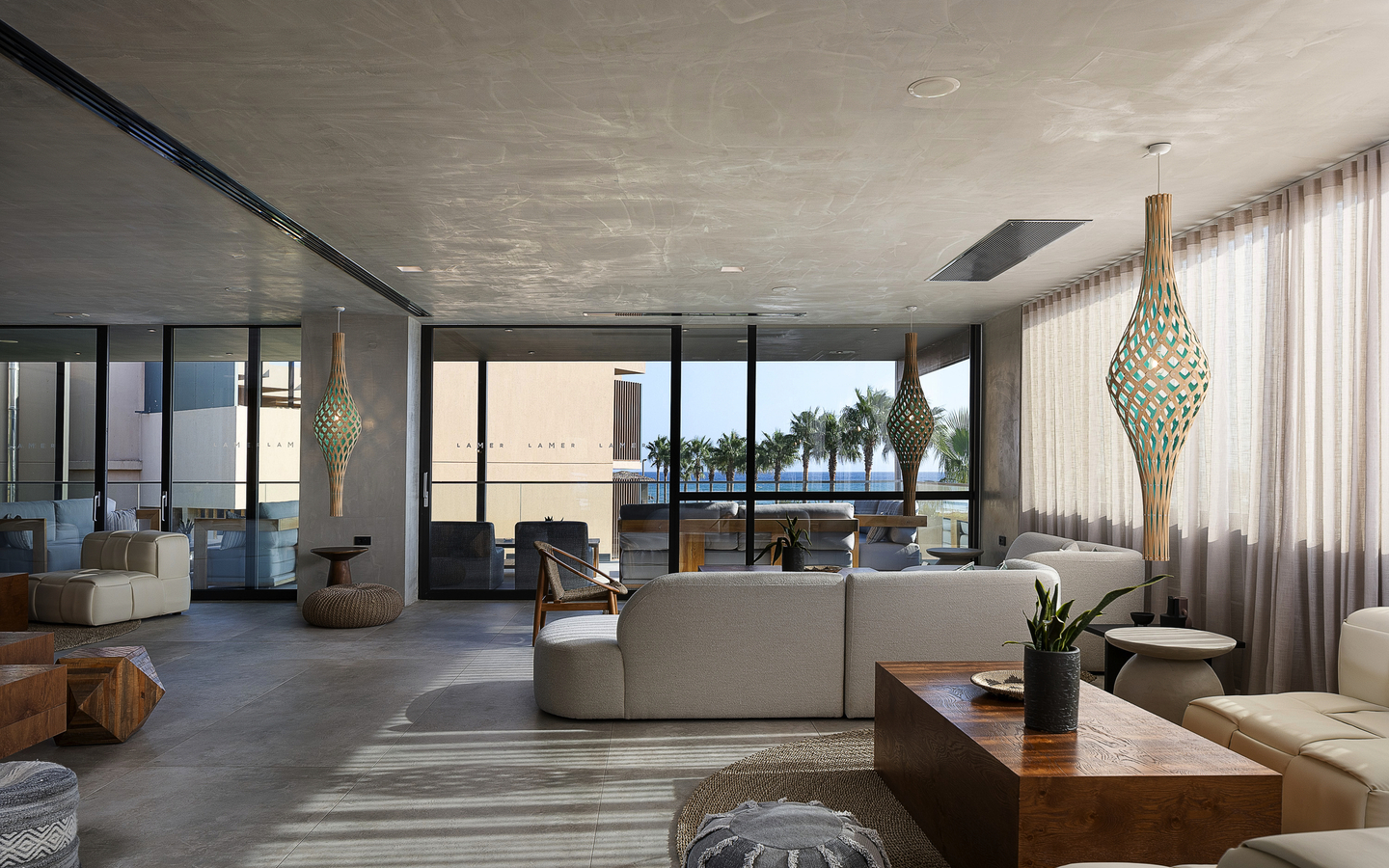 Moderne Hotellobby mit Sitzgruppen und Meerblick durch große Fenster.