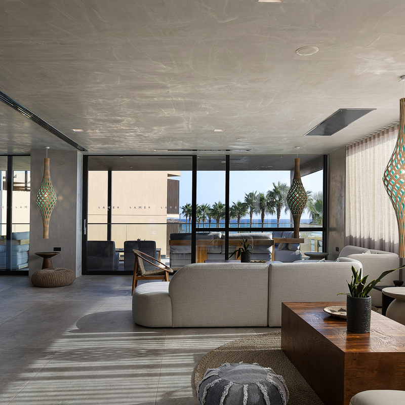 Moderne Hotellobby mit Sitzgruppen und Meerblick durch große Fenster.