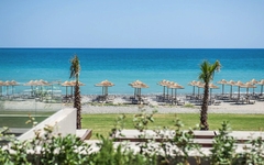 Strand mit Sonnenschirmen und klarem blauen Meer im Hintergrund.