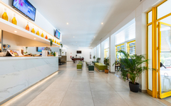 Moderne Hotelbar mit weißem Tresen und farbigen Flaschen, leere Sitzbereiche.