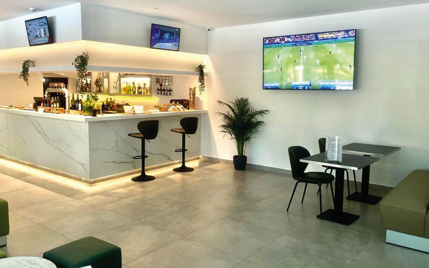 Barbereich eines modernen Hotels mit Sitzgelegenheiten und Fernsehern an der Wand.