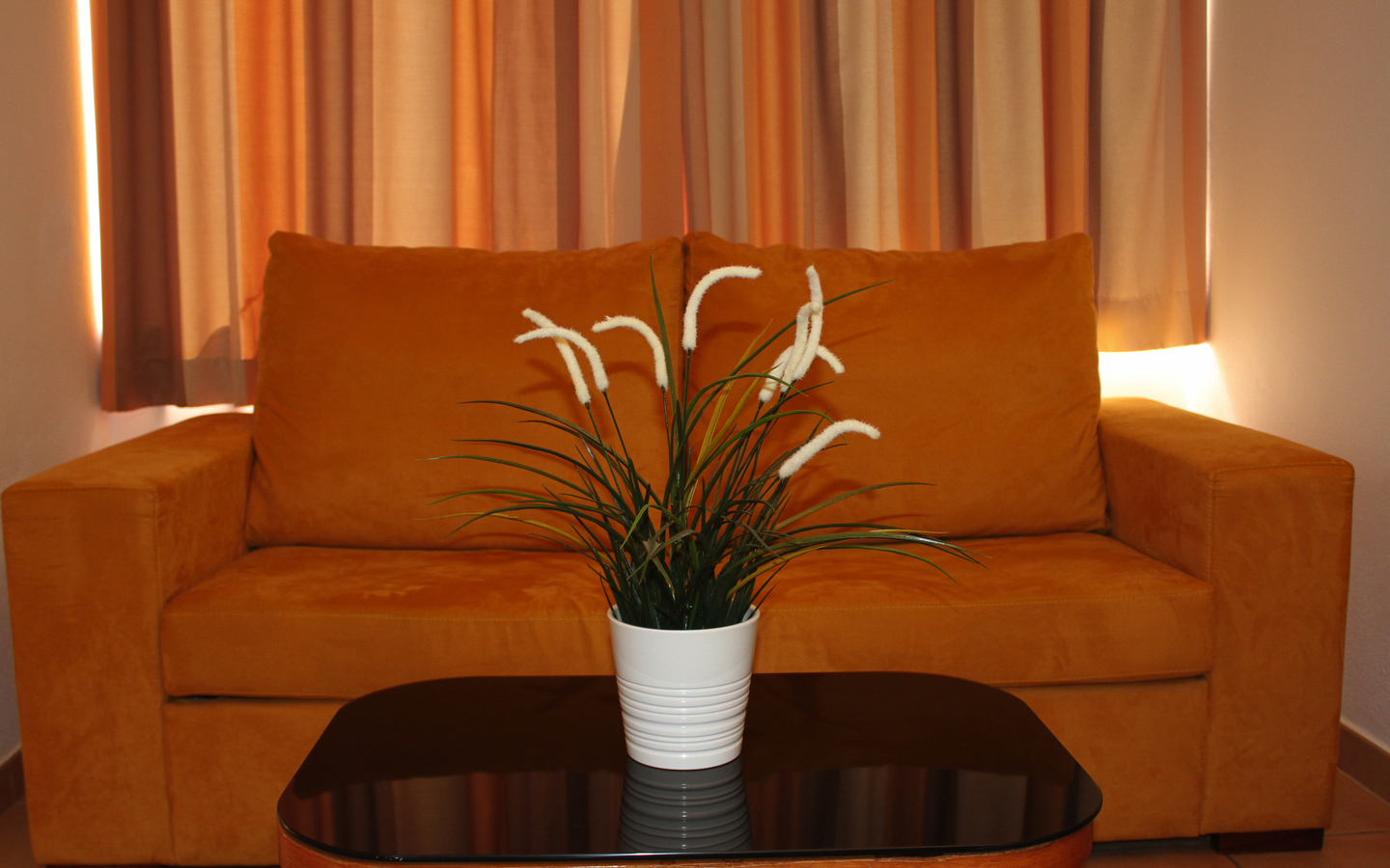 Gelbes Sofa mit Zierpflanze auf einem Couchtisch im Hotelzimmer.