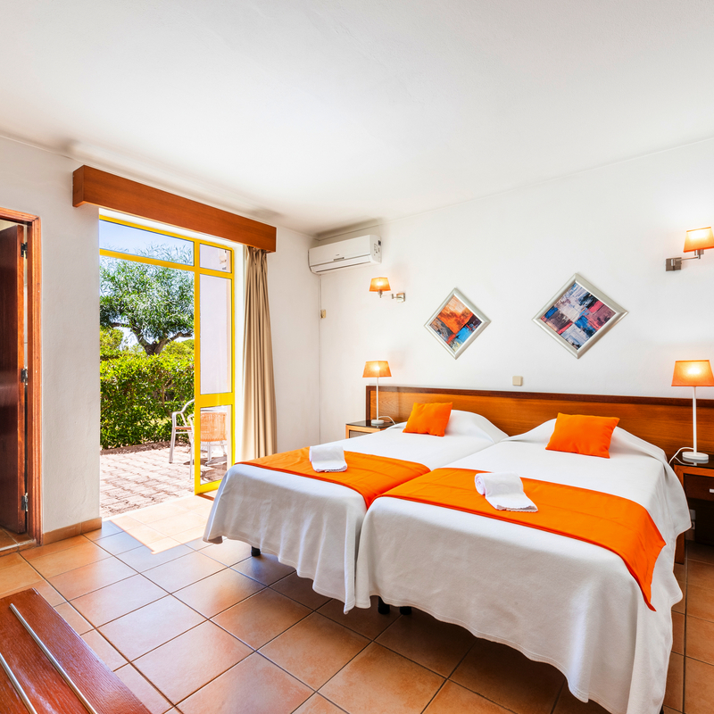 Helles Hotelzimmer mit zwei Betten, Balkon und angrenzendem Bad.