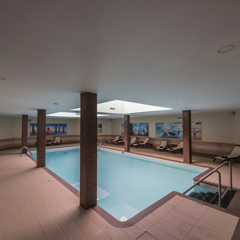 Innenbereich eines Hotelpools mit Liegestühlen und Wandbildern