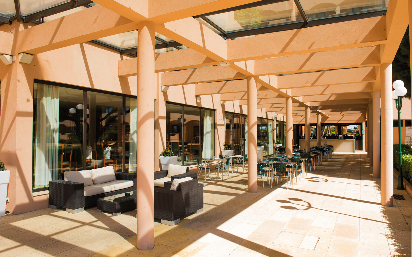 Terrasse mit Tischen und Stühlen am Hotel Vila Galé Atlântico in der Algarve, Portugal.