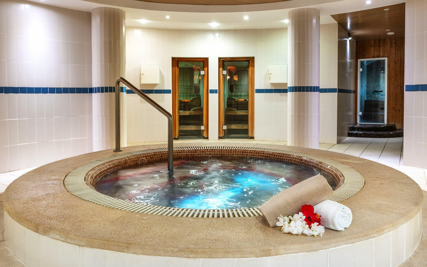 Jacuzzi in einem Hotelspa mit Handtuch und Blumenarrangement am Rand