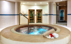 Jacuzzi in einem Hotelspa mit Handtuch und Blumenarrangement am Rand