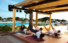 Personen machen Gymnastikübungen im Freien neben einem Pool im Adriana Beach Club Resort.