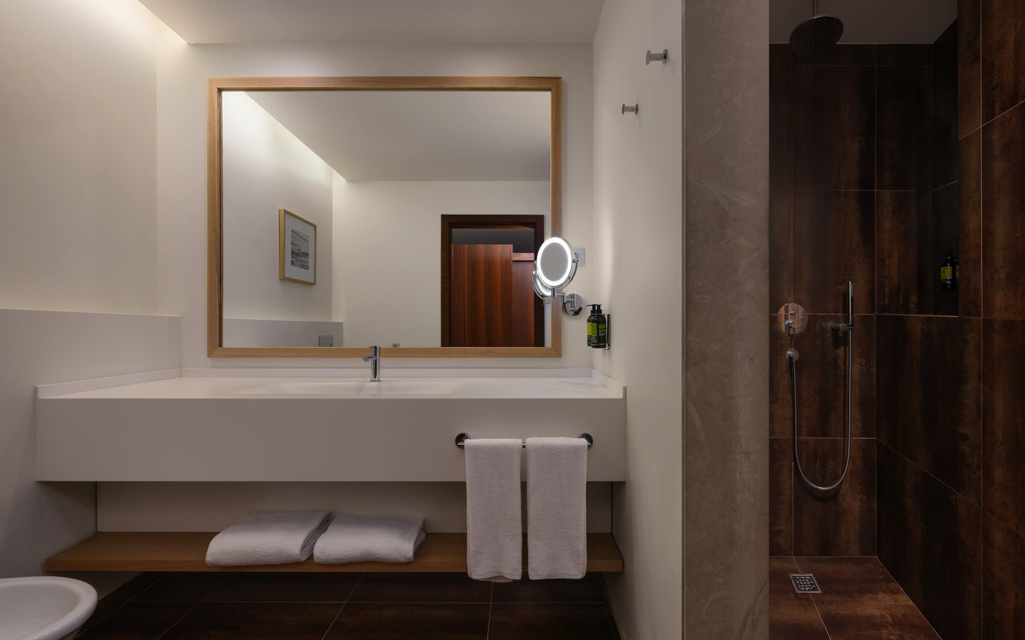 Modernes Hotelbad mit großem Spiegel, Waschbecken und offener Dusche.