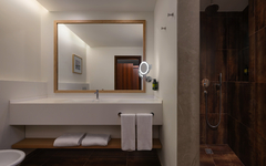 Modernes Hotelbad mit großem Spiegel, Waschbecken und offener Dusche.