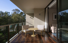 Balkon mit Sitzmöbeln, Blick ins Grüne, Teil eines Hotelzimmers.