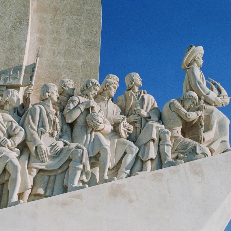 Statue von Entdeckern in einem Boot vor blauem Himmel.