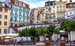 Städtische Szene mit bunten Gebäuden und Menschen in einem Straßencafé.