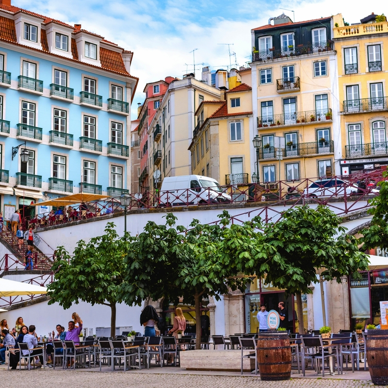 Städtische Szene mit bunten Gebäuden und Menschen in einem Straßencafé.