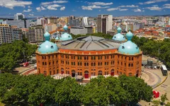 Luftaufnahme einer historischen Stierkampfarena in einer Stadt mit blauen Kuppeln.