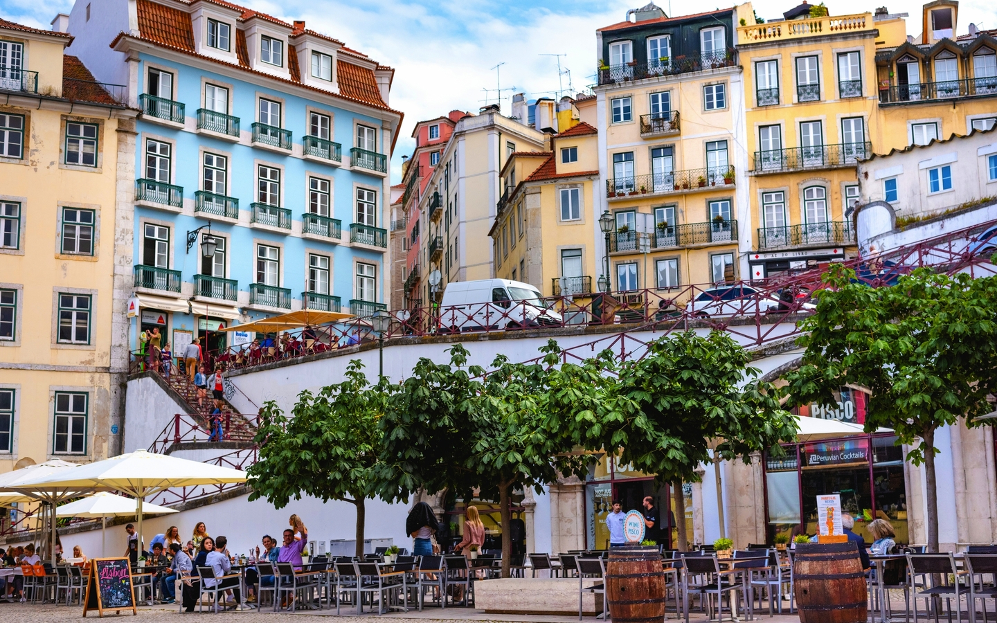 Städtische Szene mit bunten Gebäuden und Menschen in einem Straßencafé.