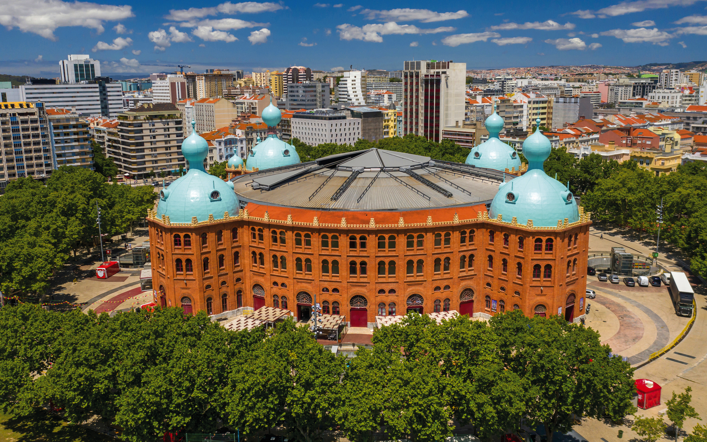 Luftaufnahme einer historischen Stierkampfarena in einer Stadt mit blauen Kuppeln.