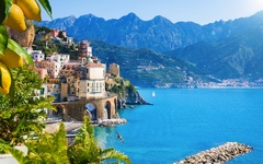 Küstenstadt mit bunten Gebäuden am Meer vor Bergkulisse.