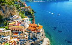 Küstenstadt mit bunten Häusern und Kirche am Meer.