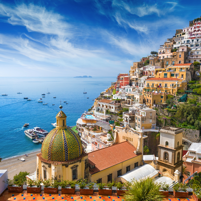 Küstenstadt Positano in Italien mit bunten Gebäuden und blauer Küste.