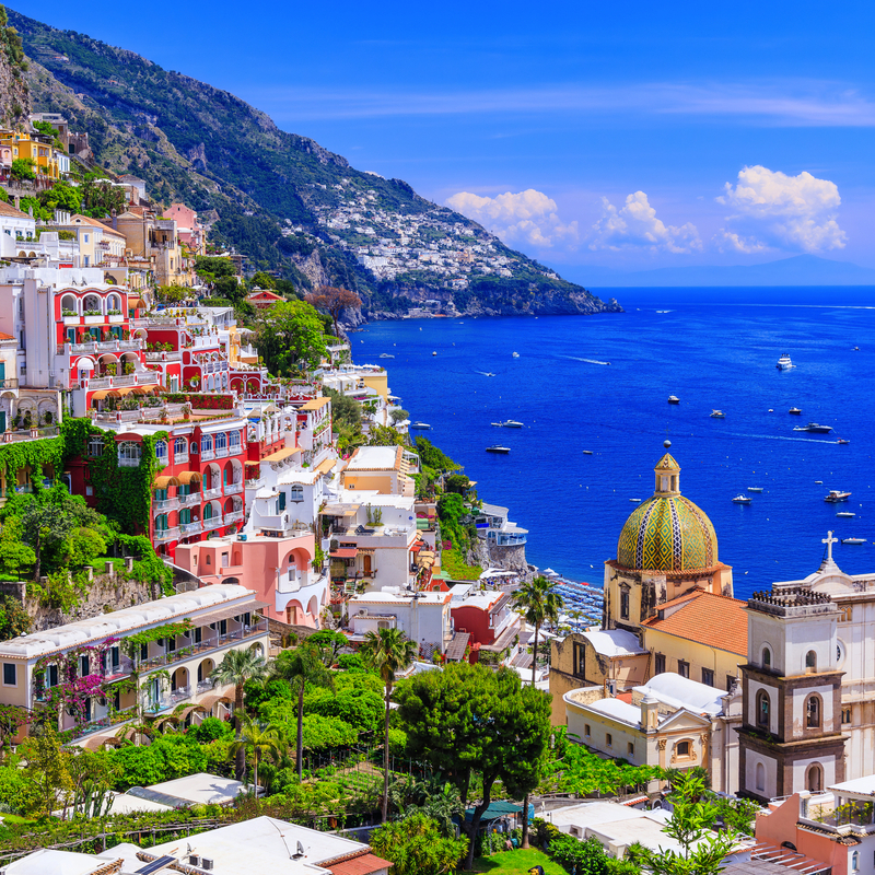 Küstenstadt mit bunten Gebäuden und Kirche am blauen Meer.