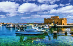 Hafen mit Booten vor Paphos Schloss auf Zypern bei blauem Himmel.