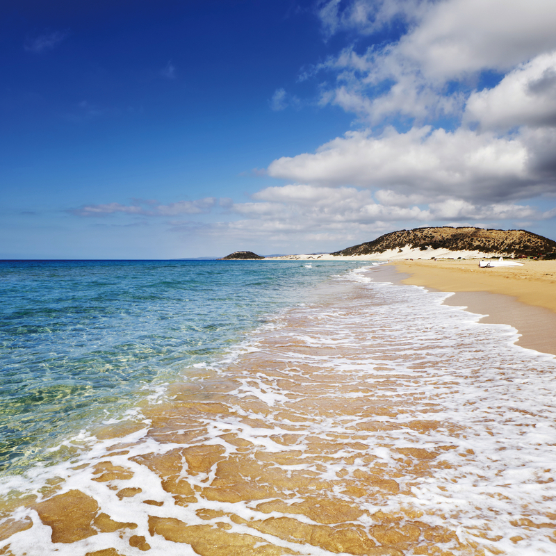 Strand mit goldenem Sand und türkisblauem Meer unter blauem Himmel in Zypern.
