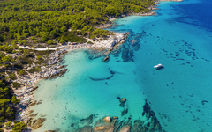Luftaufnahme einer Küste mit klarem Wasser und einem Boot.