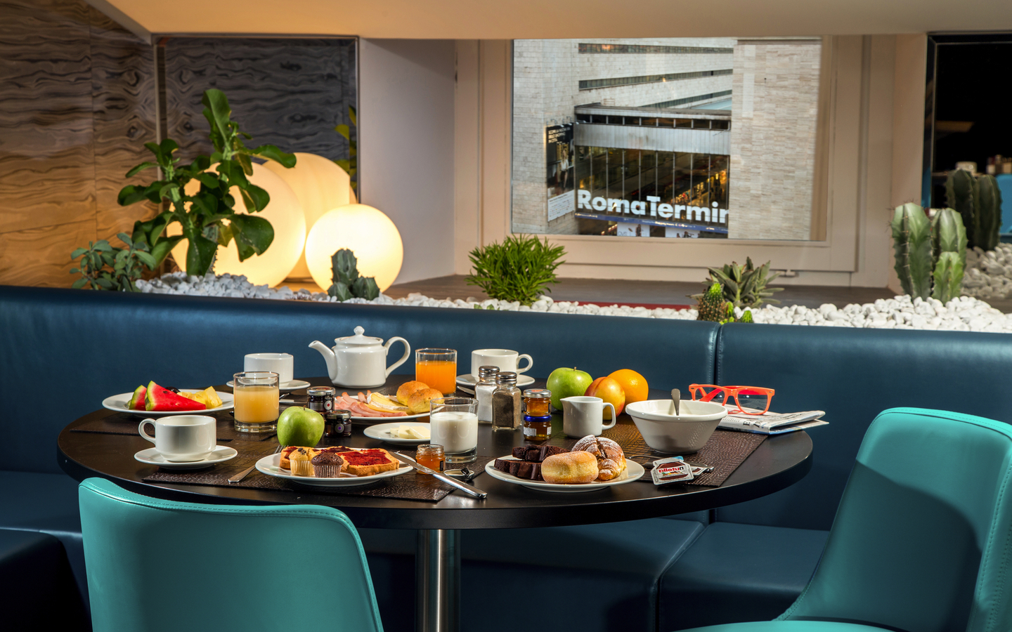 Frühstückstisch in einem Hotel mit Blick auf Rom Termini und Pflanzen im Hintergrund.