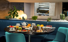 Frühstückstisch in einem Hotel mit Blick auf Rom Termini und Pflanzen im Hintergrund.